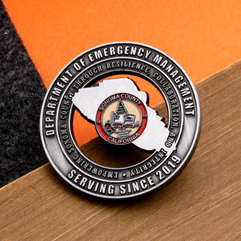 Antique silver challenge coin for the Sonoma County Department of Emergency Management featuring a cut-out design and color emblem.