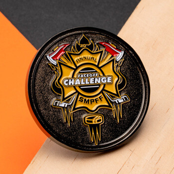 Black and gold Faceoff Challenge SMPFF challenge coin with fire axes and a hockey puck on a textured background.