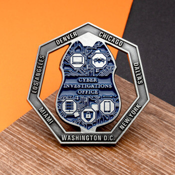 Hexagonal challenge coin for Cyber Investigations Office featuring a blue circuit board shield design and US city names on a silver frame.