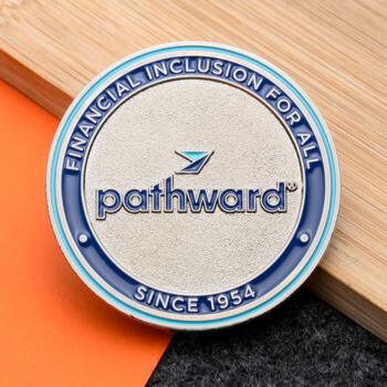 Pathward round challenge coin with blue enamel border and textured silver center on a wooden surface.