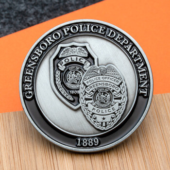 Antiqued silver challenge coin featuring the Greensboro Police Department name, 1889 date, and two detailed officer badges.