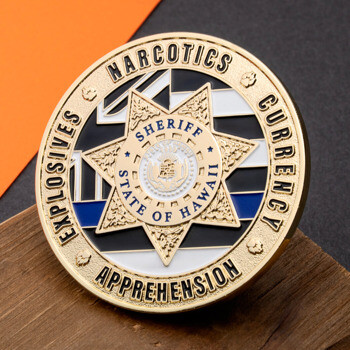 Gold Sheriff State of Hawaii challenge coin with narcotics, currency, explosives, and apprehension text on a black and white background.