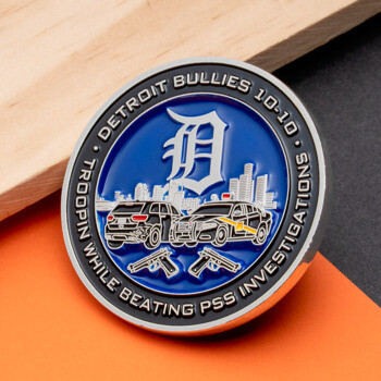 Enamel challenge coin featuring Detroit Bullies 10-10 text, a city skyline, police vehicles, and crossed pistols on a blue background.