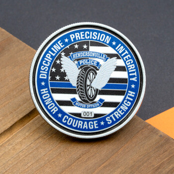 Round Hendersonville Police Motor Officer challenge coin featuring a winged tire emblem over a blue line American flag design.