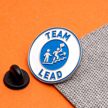 Circular Team Lead lapel pin with blue and white enamel detailing next to a black rubber clutch.
