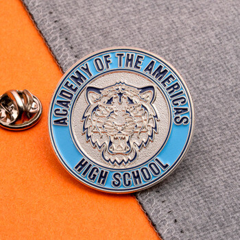 Academy of the Americas High School round lapel pin with a light blue outer border and embossed tiger mascot head next to butterfly clutch.